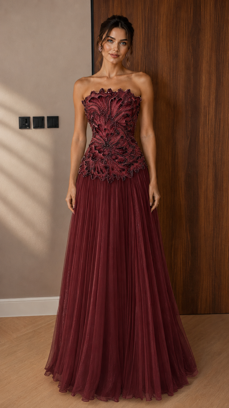 Front view of burgundy strapless appliqu¨¦ formal dress with floor-length pleated skirt